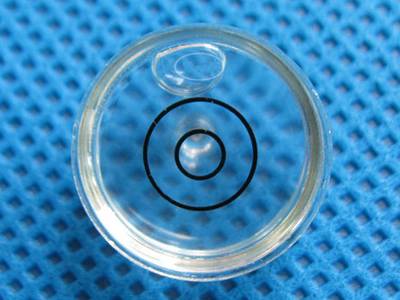 There is a transparent glass universal spirit level vial on the ground.